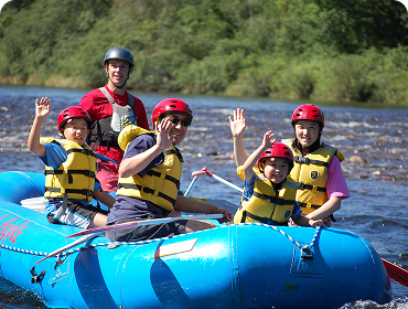 A family in a raft smiling and waving