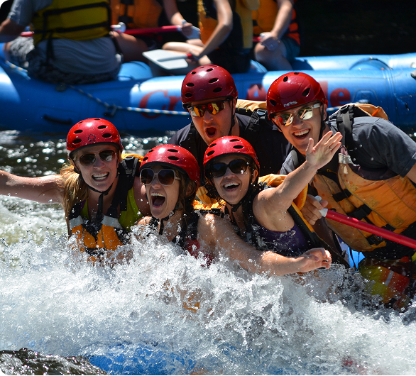 People smiling in water next to a raft
